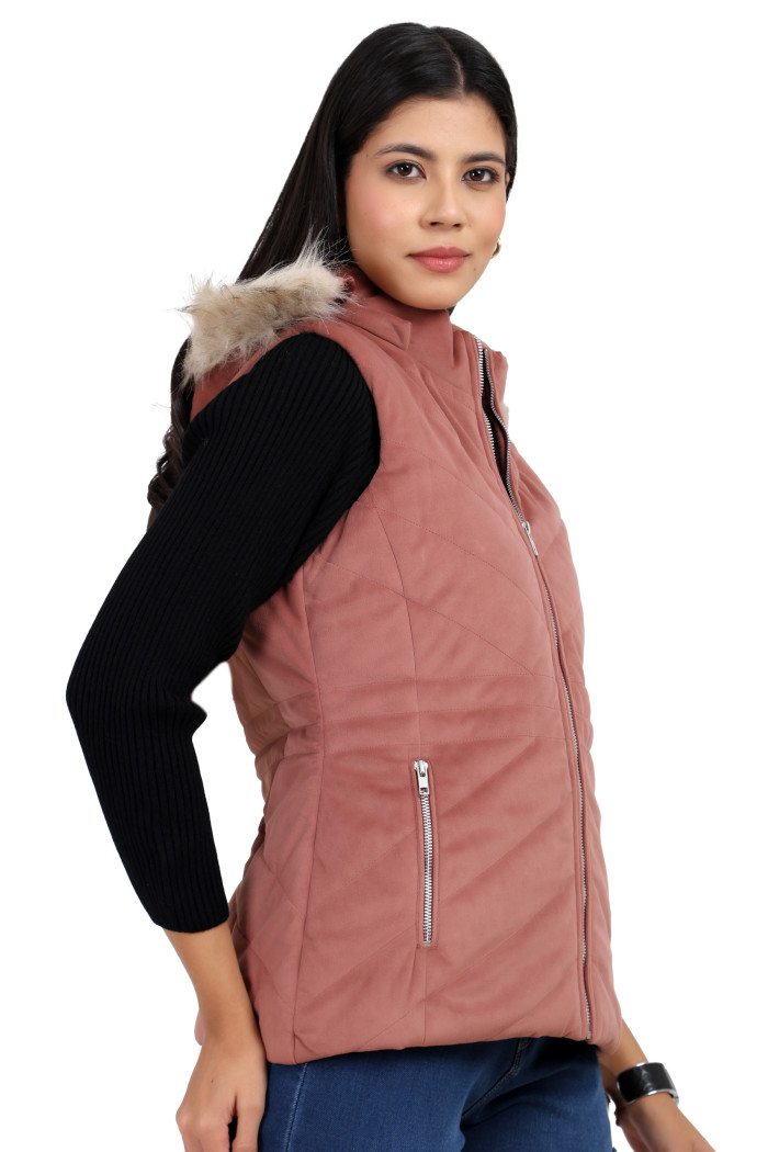 A woman is giving a standing side pose wearing Coatsnmore’s half sleeves jacket in onion pink colour with a textured pattern, removable hood with faux fur trim, side zippered pockets, a zip closure and blue jeans.